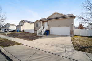 View of front of home with stone siding, fence, and concrete driveway