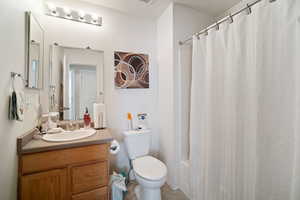 Bathroom with shower / tub combo, vanity, toilet, and tile patterned floors