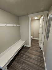 Interior space featuring a textured ceiling, dark wood-style flooring, visible vents, and baseboards