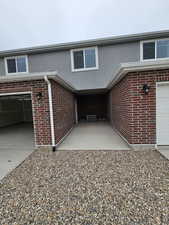 Exterior space featuring brick siding, stucco siding, a garage, cooling unit, and driveway