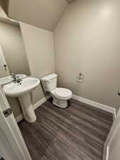 Bathroom with lofted ceiling, wood finished floors, toilet, and baseboards