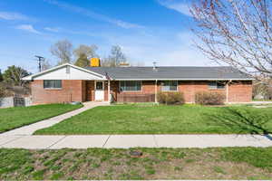 Single story home featuring brick siding and a front lawn