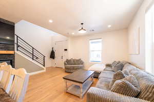 Living room with a fireplace, recessed lighting, visible vents, light wood-style flooring, and stairs