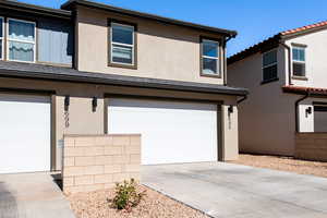 View of front of house with a garage, driveway, a tiled roof, and stucco siding