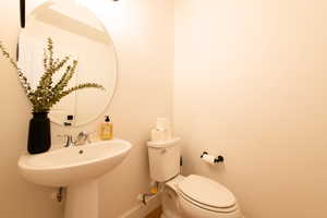 Half bath with baseboards, a sink, and toilet