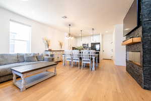 Living area featuring a fireplace, visible vents, light wood-style flooring, an inviting chandelier, and a textured ceiling