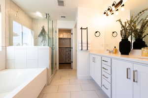 Full bathroom featuring a stall shower, visible vents, a garden tub, and double vanity