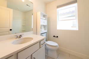 Bathroom with tile patterned flooring, toilet, vanity, baseboards, and a shower