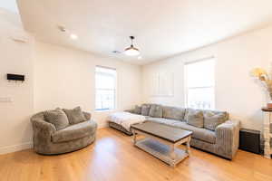 Living room featuring light wood-type flooring, baseboards, visible vents, and recessed lighting