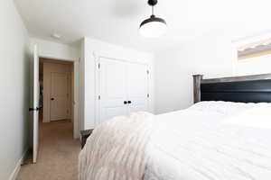 Bedroom featuring a closet, light colored carpet, and baseboards