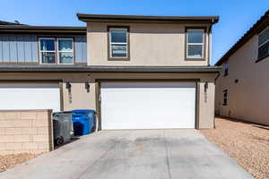 View of front facade with a garage, driveway, board and batten siding, and stucco siding