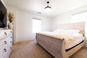 Bedroom featuring light colored carpet, visible vents, and baseboards