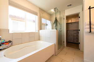 Full bath with a walk in closet, a garden tub, visible vents, a shower stall, and tile patterned flooring