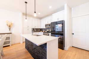 Kitchen featuring light wood-style floors, appliances with stainless steel finishes, backsplash, and a sink