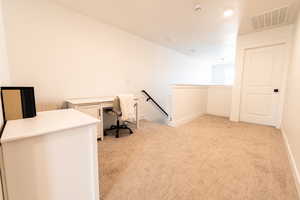 Unfurnished office with baseboards, visible vents, and light colored carpet