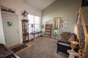 Carpeted foyer entrance with vaulted ceiling, stairs, and baseboards