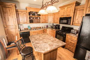 Kitchen with a center island, light countertops, light wood-type flooring, black appliances, and a sink