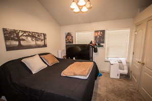 Bedroom with carpet flooring, vaulted ceiling, and an inviting chandelier