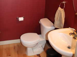 Half bathroom with a sink, wood finished floors, toilet, and baseboards