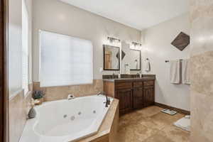 Bathroom with a relaxing tiled tub, vanity, and tile patterned floors