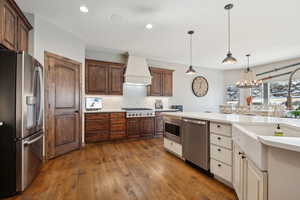 Kitchen featuring premium range hood, tasteful backsplash, dark hardwood / wood-style floors, pendant lighting, and stainless steel appliances