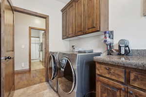 Washroom featuring cabinets, light tile patterned floors, and independent washer and dryer