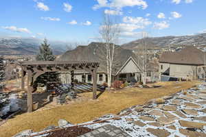 Rear view of property with a mountain view and a pergola