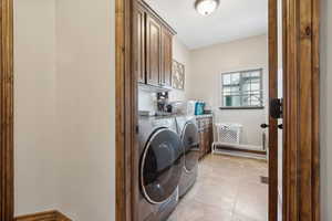 Laundry room featuring light tile patterned floors, washing machine and dryer, and cabinets