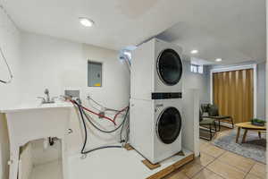 Washroom featuring light tile patterned floors, stacked washer and dryer, recessed lighting, laundry area, and electric panel