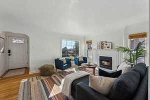 Living area with light wood-type flooring, a glass covered fireplace, and baseboards