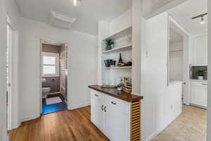 Corridor featuring light wood-type flooring, visible vents, and baseboards