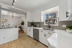 Kitchen with dishwasher, tasteful backsplash, a sink, and white cabinets