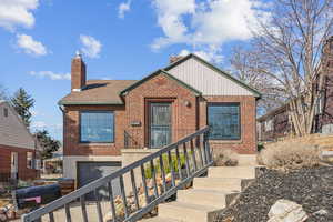 View of front of property featuring a garage, roof with shingles, brick siding, and a chimney