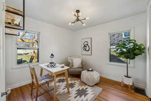 Living area featuring baseboards, visible vents, an inviting chandelier, and wood finished floors