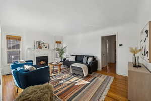 Living area with light wood-style floors, visible vents, a lit fireplace, and baseboards