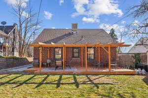 Rear view of house featuring brick siding, a yard, a shingled roof, a fenced backyard, and a wooden deck