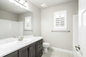 Full bath featuring baseboards, toilet, walk in shower, and vanity
