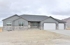 Ranch-style home with stone siding, stucco siding, an attached garage, and concrete driveway