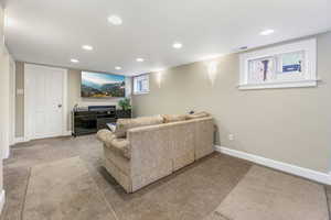 Carpeted living area with baseboards, visible vents, and recessed lighting