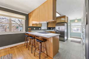 Kitchen featuring a textured ceiling, stainless steel appliances, a peninsula, visible vents, and baseboards