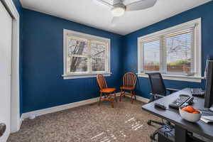 Carpeted home office with ceiling fan and baseboards