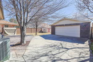 Exterior space with central AC, brick siding, an outdoor structure, and fence