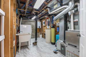 Unfinished basement featuring water heater and marble finish floor