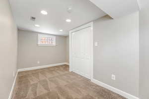 Below grade area with carpet, visible vents, baseboards, and recessed lighting