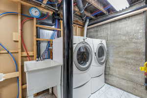 Clothes washing area featuring washing machine and dryer, laundry area, and a sink