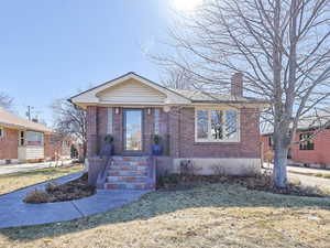 Bungalow-style home with a chimney, a front lawn, and brick siding