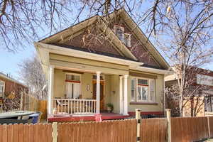 View of front of property featuring a fenced front yard, covered porch, and a shingled roof