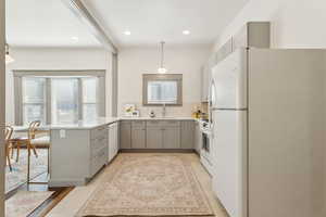 Kitchen with gray cabinets, light quartz countertops, white appliances.