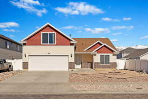 View of front of property featuring driveway, an attached garage, and fence