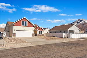 View of front of home featuring driveway, an attached garage, fence, and a mountain view